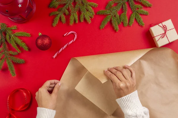 Empacotamento de presentes de Natal. Mãos femininas embalando caixa de presente de Natal em papel artesanal — Fotografia de Stock