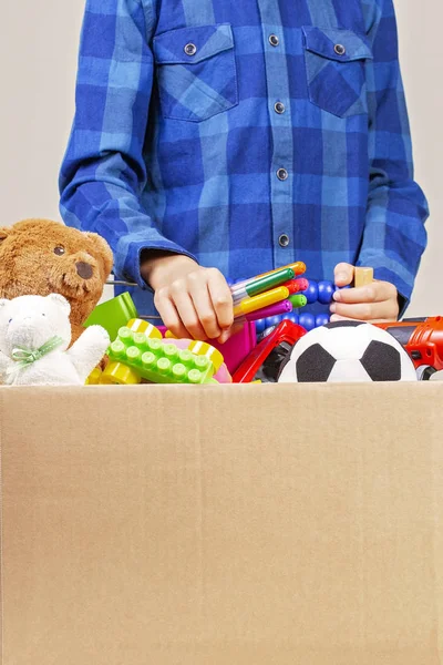 Concetto di donazione. Bambino con scatola donare con vestiti, libri, materiale scolastico e giocattoli — Foto Stock