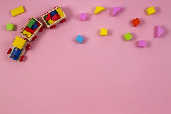 Oyuncak arka plan. Ahşap oyuncak tren pembe bir arka plan üzerinde renkli küpler — Stok fotoğraf