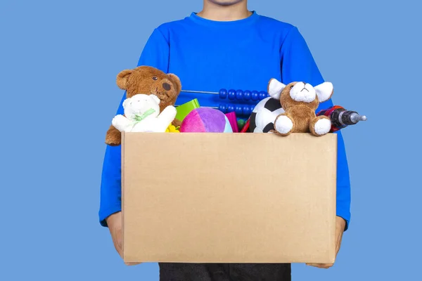 Concepto de donación. Niño sosteniendo donar caja con ropa, libros y juguetes —  Fotos de Stock