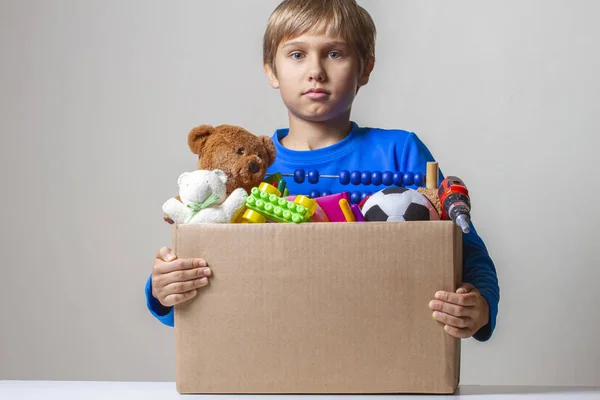 Conceito de doação. Kid holding doar caixa com roupas, livros e brinquedos — Fotografia de Stock