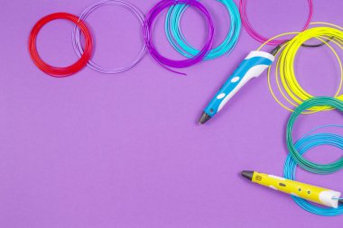 mor arka plan üzerinde renkli plastik filaman ile 3D kalemler.