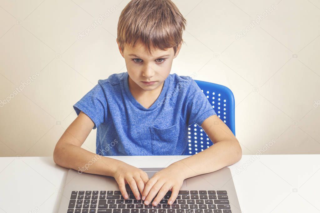 Concentrated boy typing on laptop computer