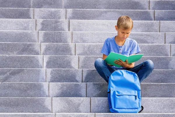 Jongen zit op de trap en school huiswerk. — Stockfoto
