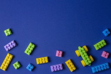 Mavi arka plan üzerinde renkli plastik oyuncak araba yapı taşları
