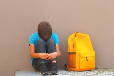 Mutsuz, yorgun çocuk tek başına açık havada yere oturmak