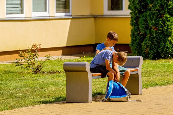 Çocuk okul bahçesinde üzgün çocuğu teselli ediyor.