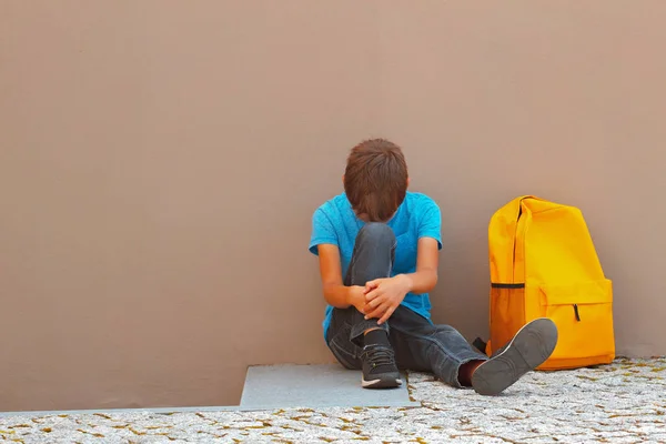 Niño triste y cansado sentado solo en el suelo al aire libre — Foto de Stock