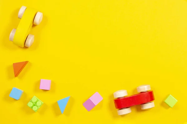 Baba gyerek játékok háttér. Fából készült kocsi, a színes téglák és a kockákat a sárga háttér — Stock Fotó