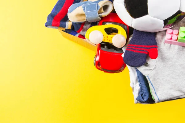 Játékok, könyvek, ruházat, sárga háttér jótékonysági adomány doboz — Stock Fotó