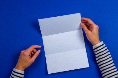 Boş beyaz el ilanı broşür kitapçık tutan eller kadın. Mockup sayfa şablonu reklam kitapçık mavi zemin üzerine