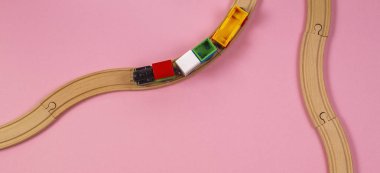 Oyuncak tren ve pembe renkli arka plan üzerinde ahşap raylar