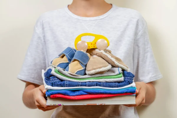 Adomány fogalma. Gyerek az ő gazdaság kezek-könyvek, ruhák és a szeretet játékok — Stock Fotó