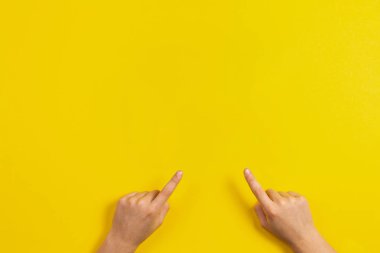 Sarı zemin üzerine bir şey işaret eden çocuk eller