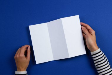 Boş beyaz el ilanı broşür kitapçık tutan eller kadın. Mockup sayfa şablonu reklam kitapçık mavi zemin üzerine
