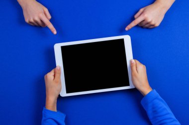 Mavi arka plan üzerinde beyaz tablet bilgisayar çocuk elinde işaret eden çocuk eller