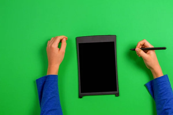 Çocuk el yeşil arka plan üzerinde grafik tablet ve stylus kalem ile — Stok fotoğraf