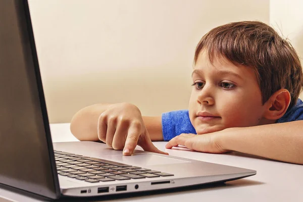 Ragazzo seduto alla scrivania con computer portatile e navigazione, guardare video o giochi — Foto Stock