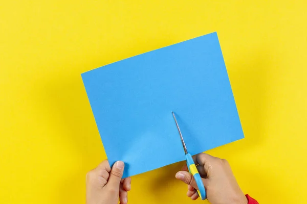 Kids hands cutting colored paper with scissors Stock Photo