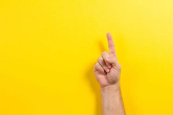 Ember kéz a mutatja egy ujjal, sárga háttér — Stock Fotó