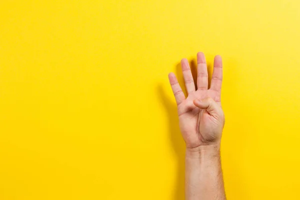 Ember kéz mutató négy ujja sárga háttéren. Két szám szimbólum — Stock Fotó