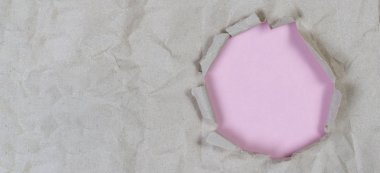 İçinde açık pembe arka plan olan eski buruşuk kağıtta bir delik