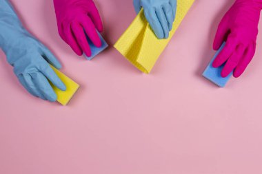 Pembe ve açık mavi kauçuk eldivenli pembe arka planda süngerli kadınlar