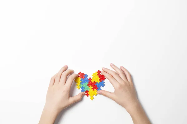 Child hands holding colorful heart on white background. World autism awareness day concept — Stock Photo, Image