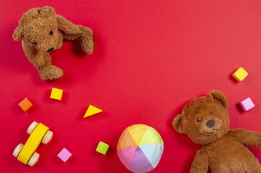 Bebek Çocuk oyuncakları arka plan. Oyuncak ayı, ahşap araba, kırmızı bir arka plan üzerinde renkli tuğlalar