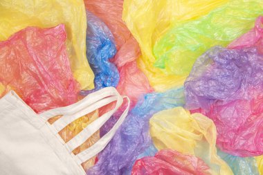 Bir eko doğal yeniden kullanılabilir alışveriş çantası arka plan ile birçok çok renkli plastik torbalar. Sıfır atık, çevre dostu, sürdürülebilirlik yaşam tarzı, hiçbir plastik kavramı