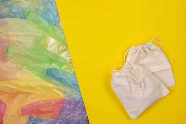 Sok színes műanyag zacskók egy eco természetes újrafelhasználható zsák a vásárlási sárga háttér. Nulla hulladék, eco barátságos, fenntartható életmód, nem műanyag koncepció — Stock Fotó