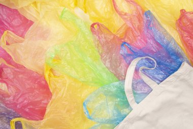 Bir eko doğal yeniden kullanılabilir alışveriş çantası arka plan ile birçok çok renkli plastik torbalar. Sıfır atık, çevre dostu, sürdürülebilirlik yaşam tarzı, hiçbir plastik kavramı