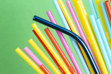 Paslanmaz çelik yeniden kullanılabilir saman plastik çöp ile yeşil arka plan üzerinde içme
