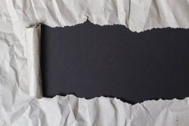 Torn crumpled package paper with black background clipart