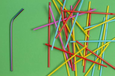 Yeşil arka plan üzerinde birçok çok renkli plastik çöp saman içme paslanmaz çelik yeniden kullanılabilir