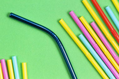 Paslanmaz çelik yeniden kullanılabilir saman plastik çöp ile yeşil arka plan üzerinde içme