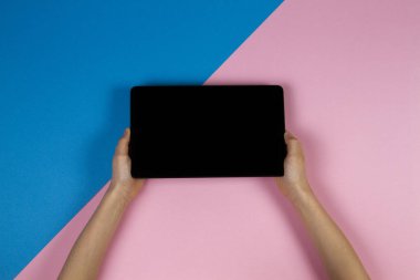 Tablet bilgisayarda pembe ve mavi arka plan ile çocuk el