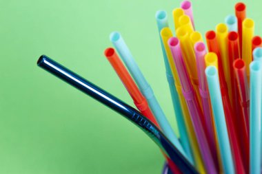 Paslanmaz çelik yeniden kullanılabilir saman plastik çöp ile yeşil arka plan üzerinde içme