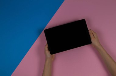 Tablet bilgisayar pembe ve mavi arka plan üzerinde holding çocuk eller