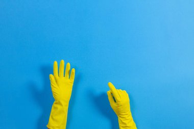 Kadın eller yukarı doğru parmağınızla, mavi arka plan üzerinde sarı lastik eldiven puanla