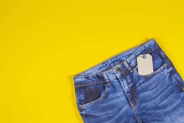 Prázdné návěsce cenovka s modré džíny na žlutém podkladu — Stock fotografie