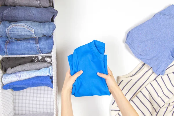 Armazenamento vertical de roupas, arrumação, conceito de limpeza de quartos. Mãos arrumando e classificando roupas de crianças na cesta . — Fotografia de Stock