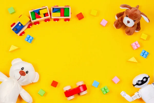 Kinderspielzeug Hintergrund. weißer Teddybär, Holzeisenbahn, Spielzeugauto, Roboter, bunte Blöcke auf gelbem Hintergrund — Stockfoto