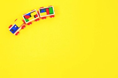 Ahşap oyuncak tren ile sarı arka plan üzerinde renkli blok