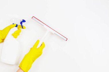 Pencere cam Temizleme Aracı ve sprey şişe deterjan ile beyaz arka plan üzerinde tutan sarı lastik eldivenli kadın eller