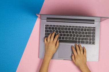 Tipik dizüstü bilgisayar klavye, üstten görünüm, pembe ve mavi arka plan üzerinde çocuk eller