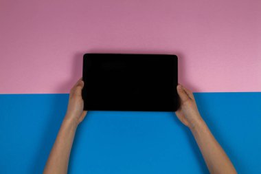 Tablet bilgisayar pembe ve mavi arka plan üzerinde holding çocuk eller