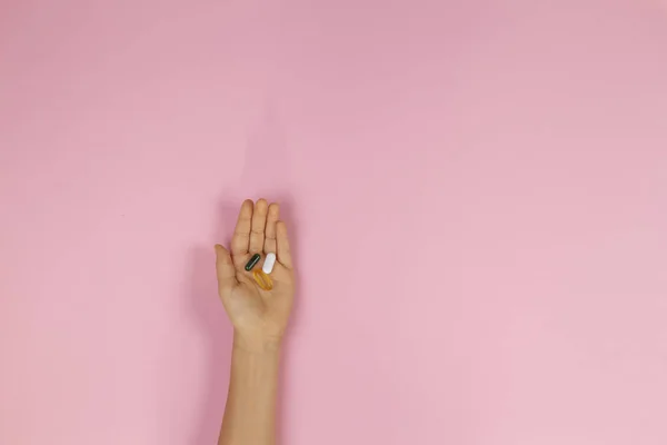 ピンクの背景に手の子供の薬カプセル — ストック写真