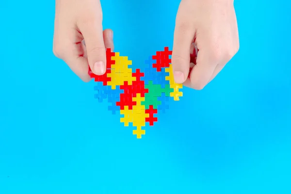 Child hand holding colorful heart on blue background. World autism awareness day concept — Stock Photo, Image