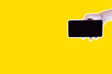 Dergi tarzı ve pop sanat tarzı kolaj. Smartphone sarı arka plan üzerinde tutan el